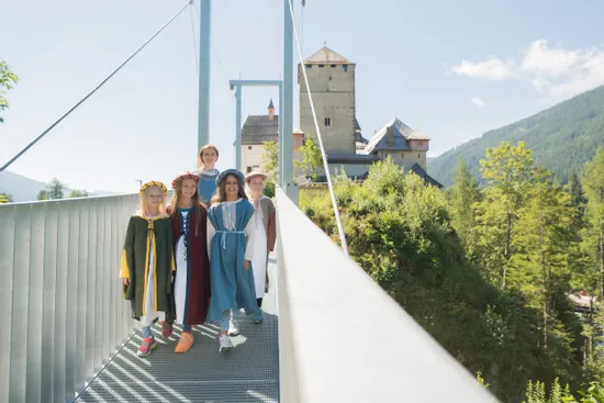 Kinder in mittelalterlichen Kostümen auf Hängebrücke bei Bergburg